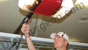 Acheson Door Surgeon garage door repair technician fixing garage door opener motor.