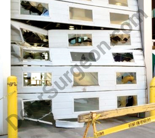 Wrecked industrial overhead garage door with broken windows.